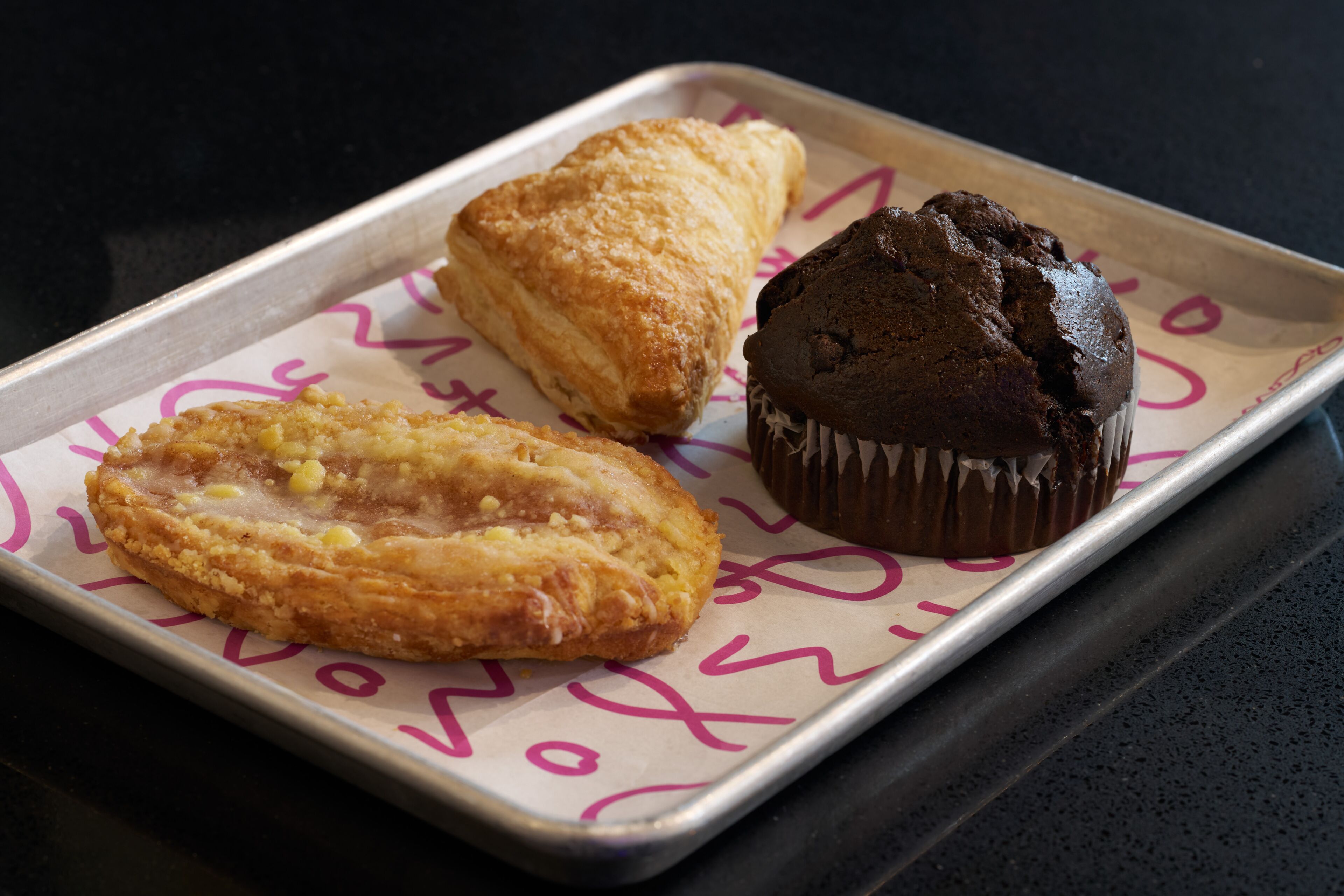 A tray with three pastries on a table.