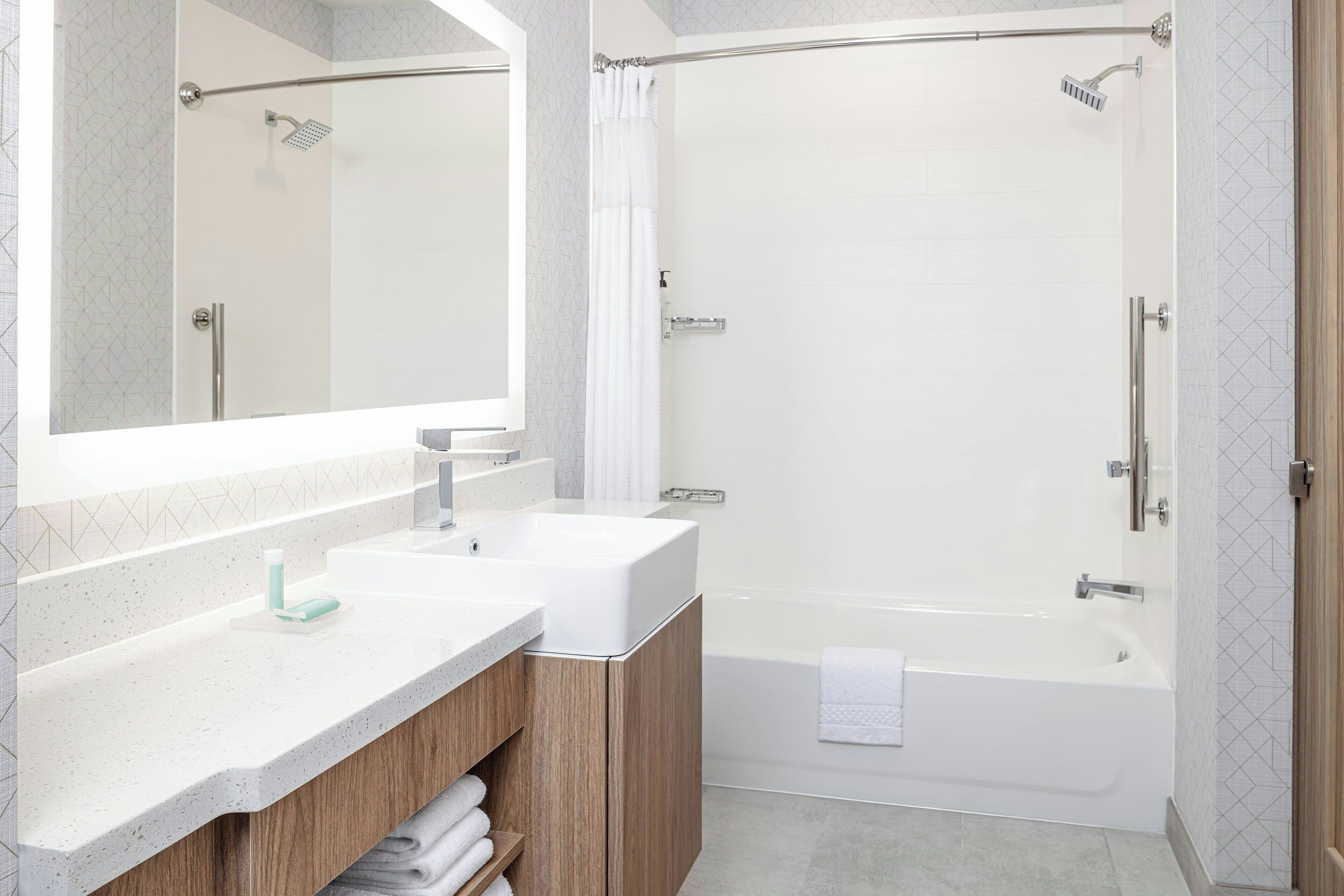 A modern bathroom with two sinks, a shower, and a bathtub.
