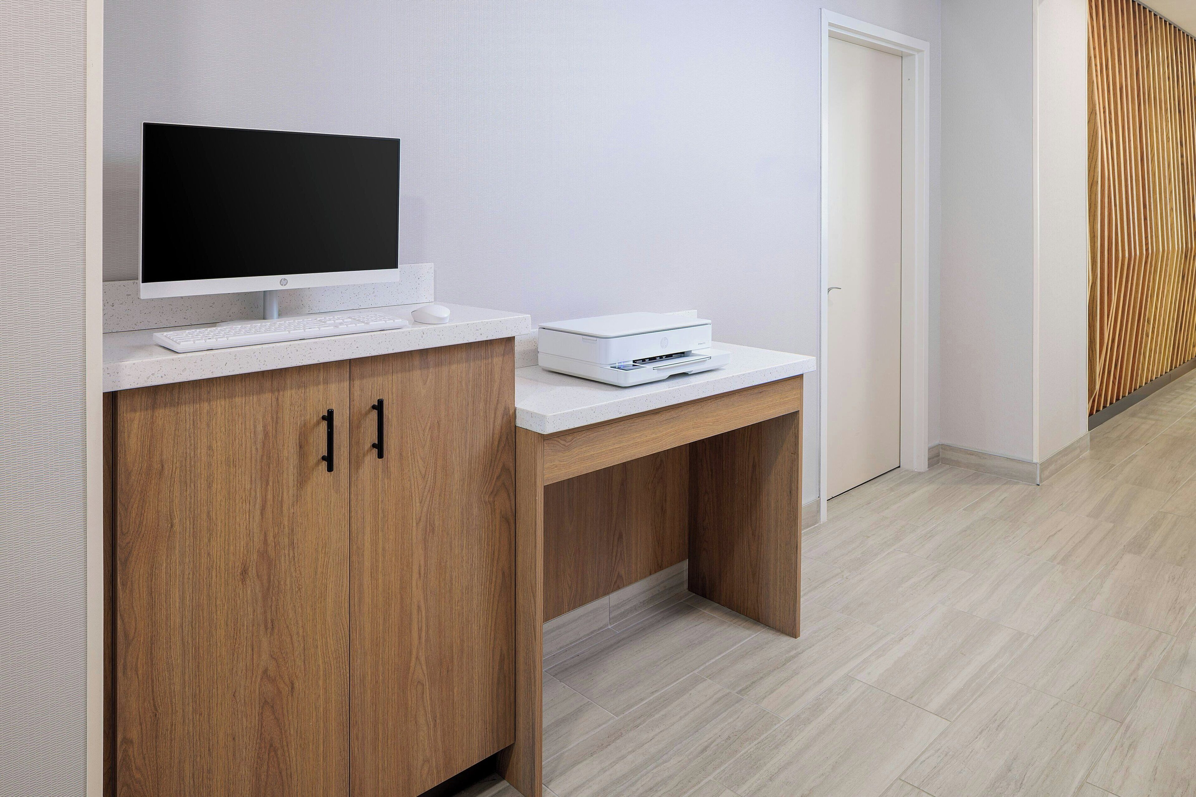 A modern office desk with a flat-screen monitor, keyboard, and printer.