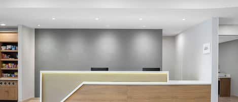 A reception desk with a modern design, a wooden counter, and a patterned wall behind it.