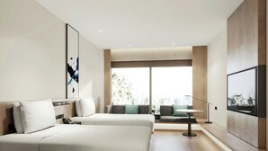 Une chambre d’hôtel moderne dotée d’un grand lit, d’un coin salon avec une table et d’une grande fenêtre offrant une vue sur l’extérieur.