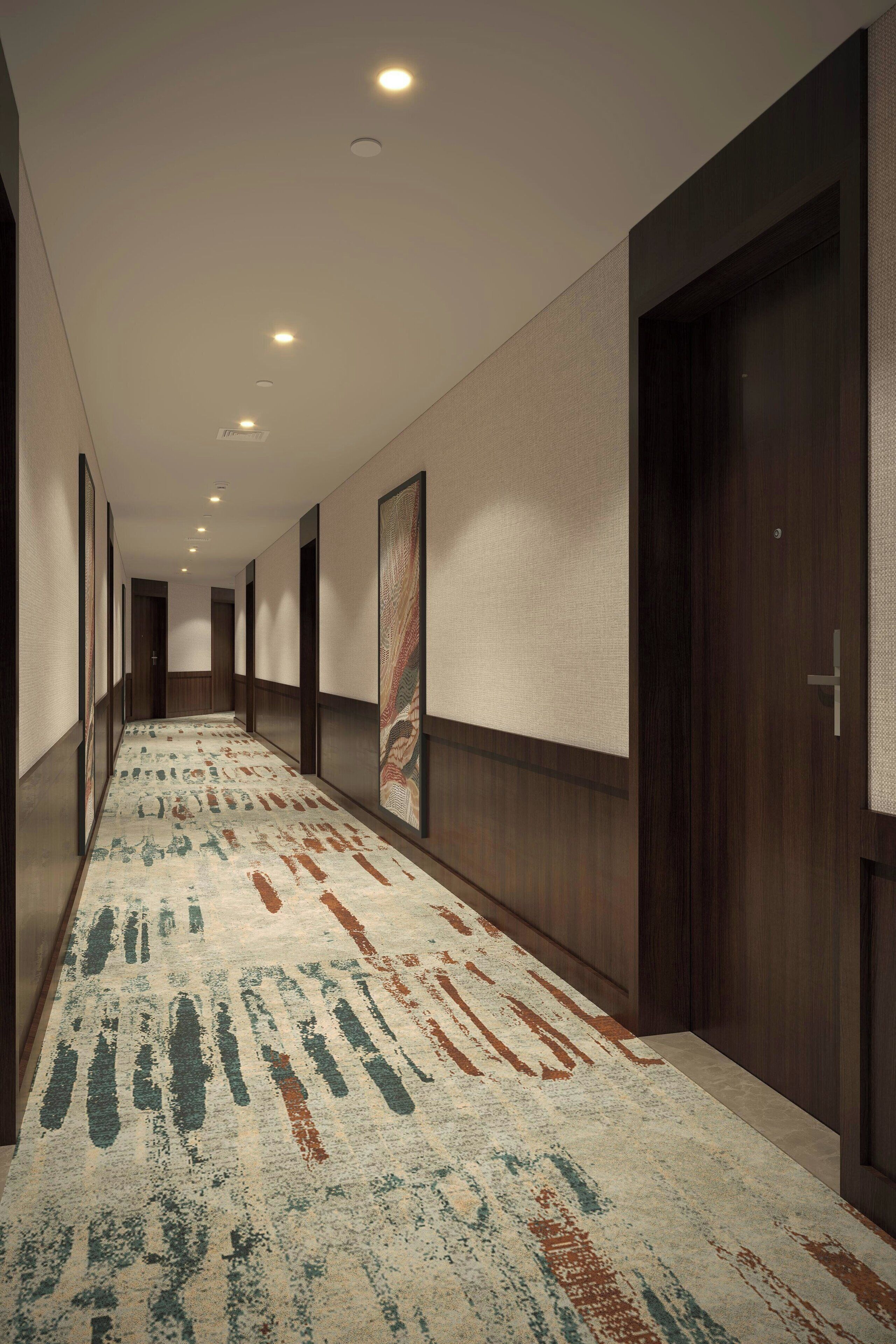 A hallway with patterned carpet, wooden doors, and recessed lighting.