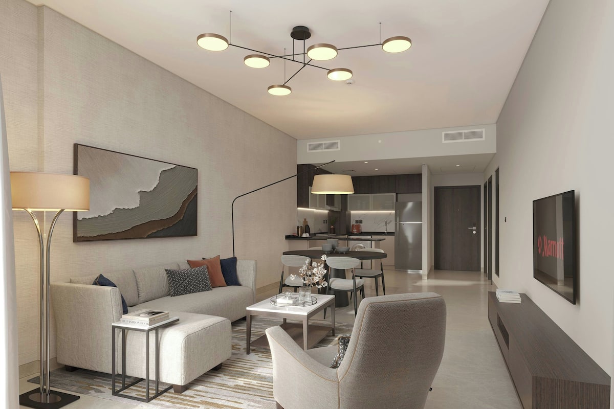 A modern living room with a sofa, armchairs, a coffee table, and a dining area with a table and chairs.