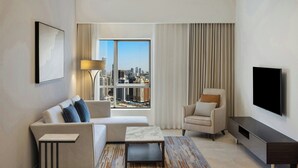 Ein modernes Wohnzimmer mit Sofa, Sessel, Couchtisch und Fernseher.
