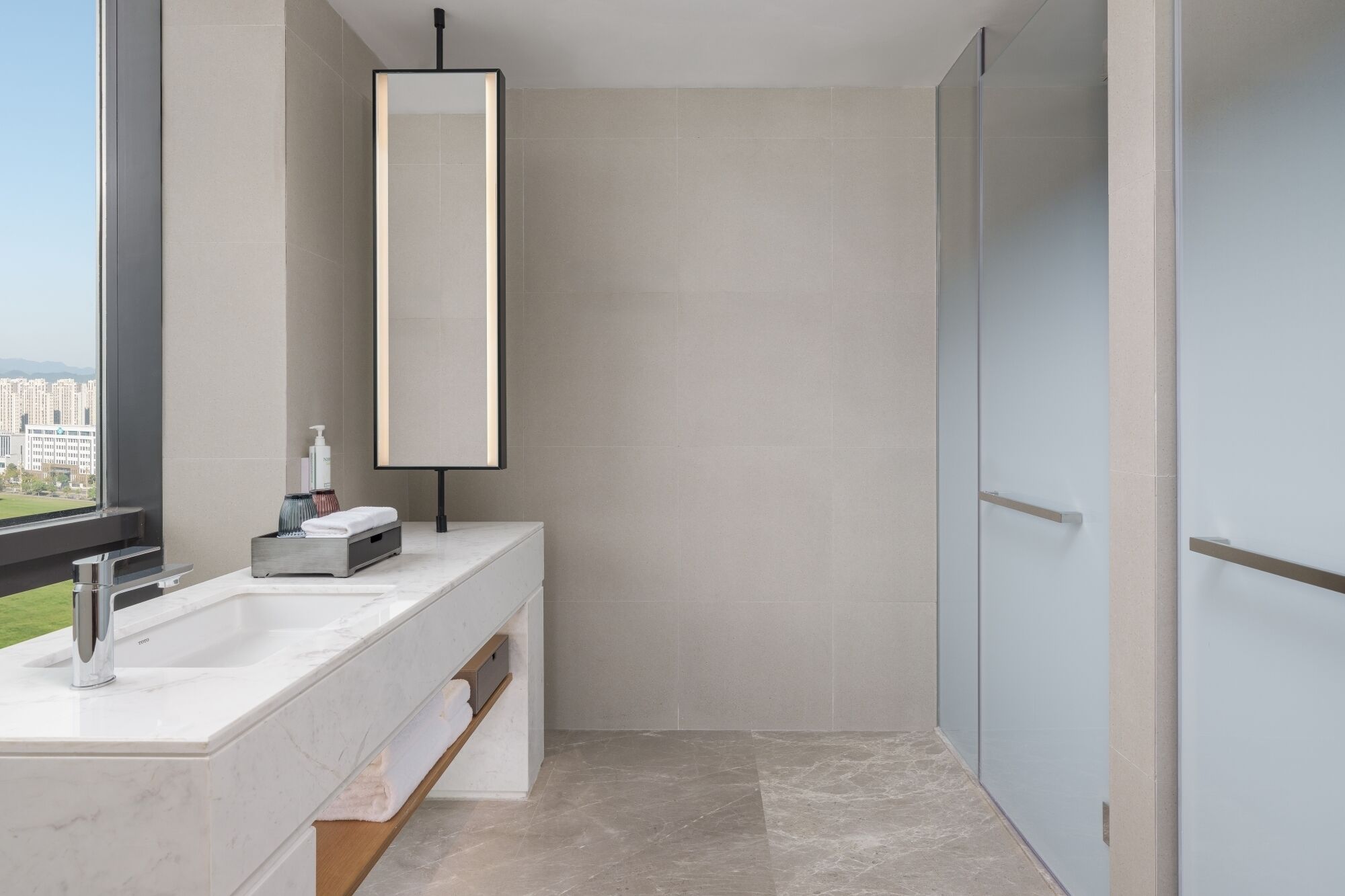 Un baño moderno con un espejo grande, un lavabo y una zona de ducha.
