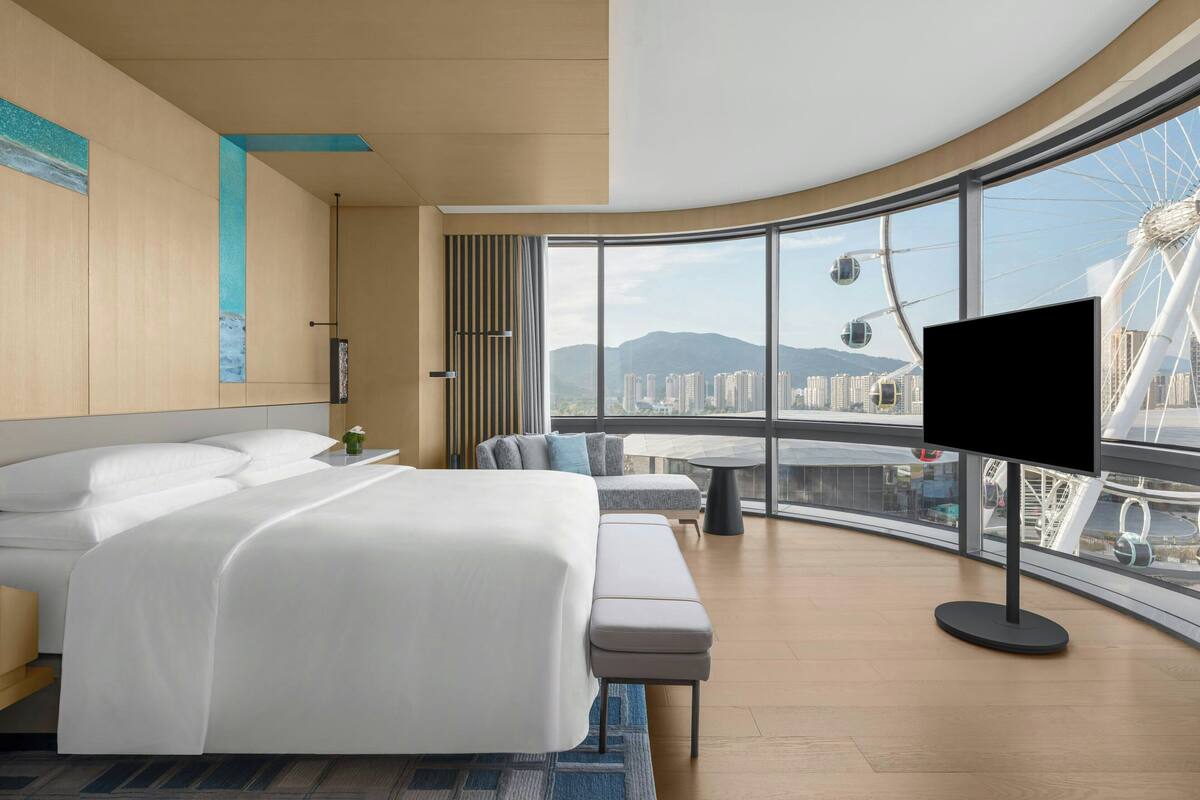 Ein modernes Hotelzimmer mit einem großen Bett, einer Sitzecke und einem Fernseher.