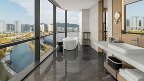 Un baño moderno con bañera, ventanas amplias y vista a la ciudad.