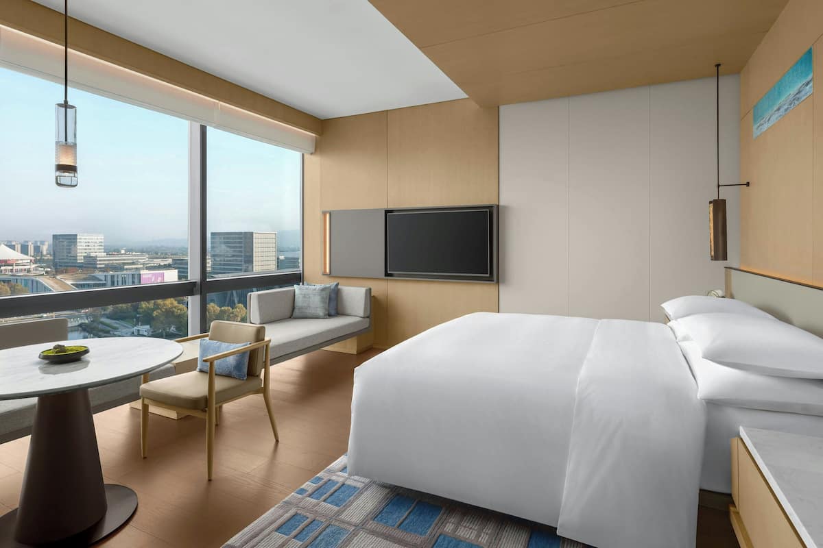 Ein modernes Hotelzimmer mit einem großen Bett, einer Couch, einem Esstisch und einem Fernseher.