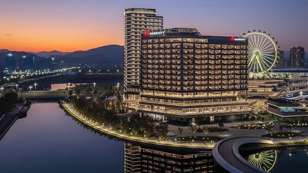 Un hotel Marriott con una noria, rodeado de agua y edificios modernos.