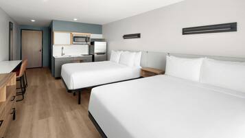 Una habitación de hotel con dos camas, un escritorio, una silla, un microondas y un lavamanos.