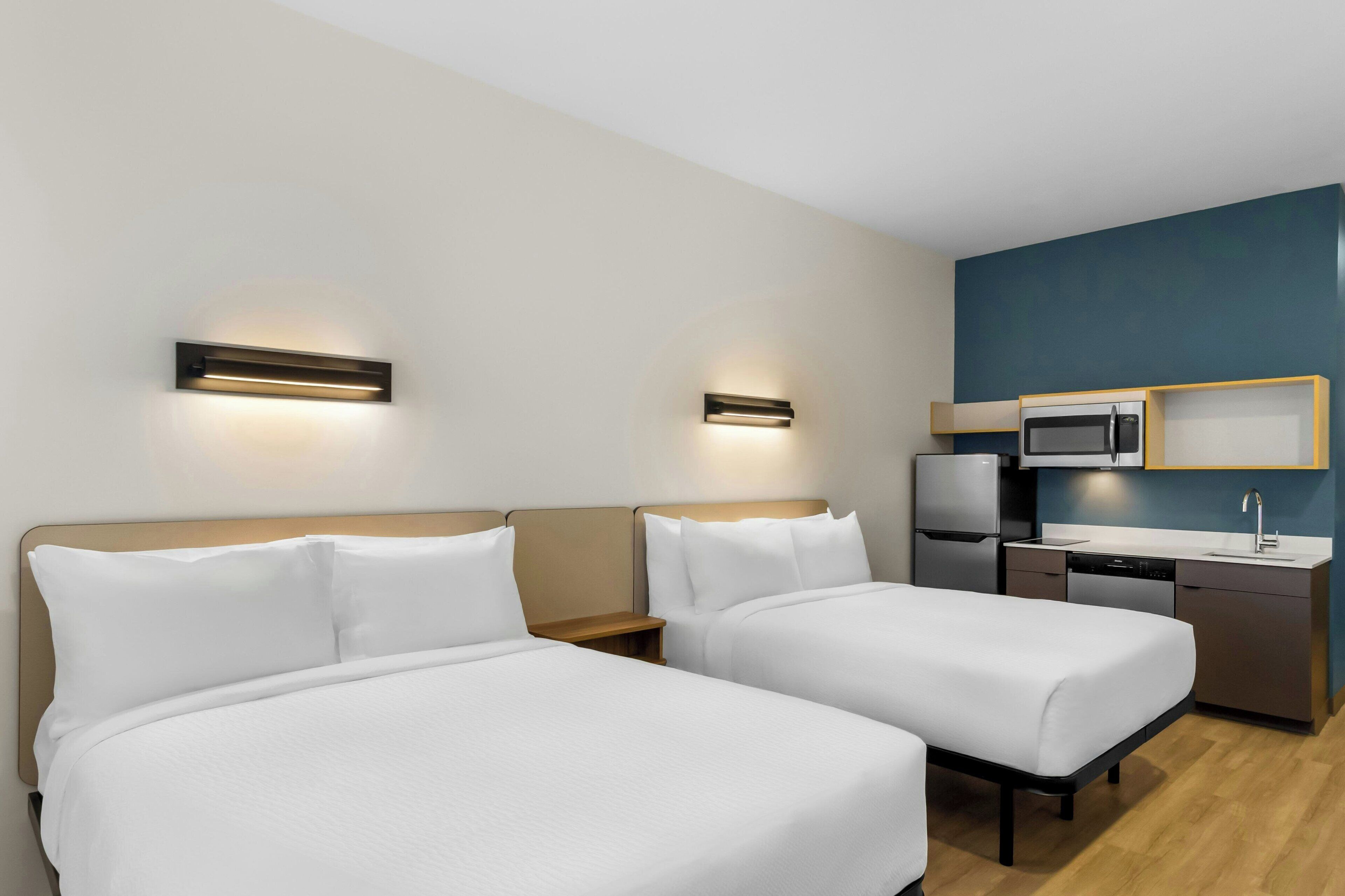 Habitación de hotel con dos camas, kitchenette y microondas.