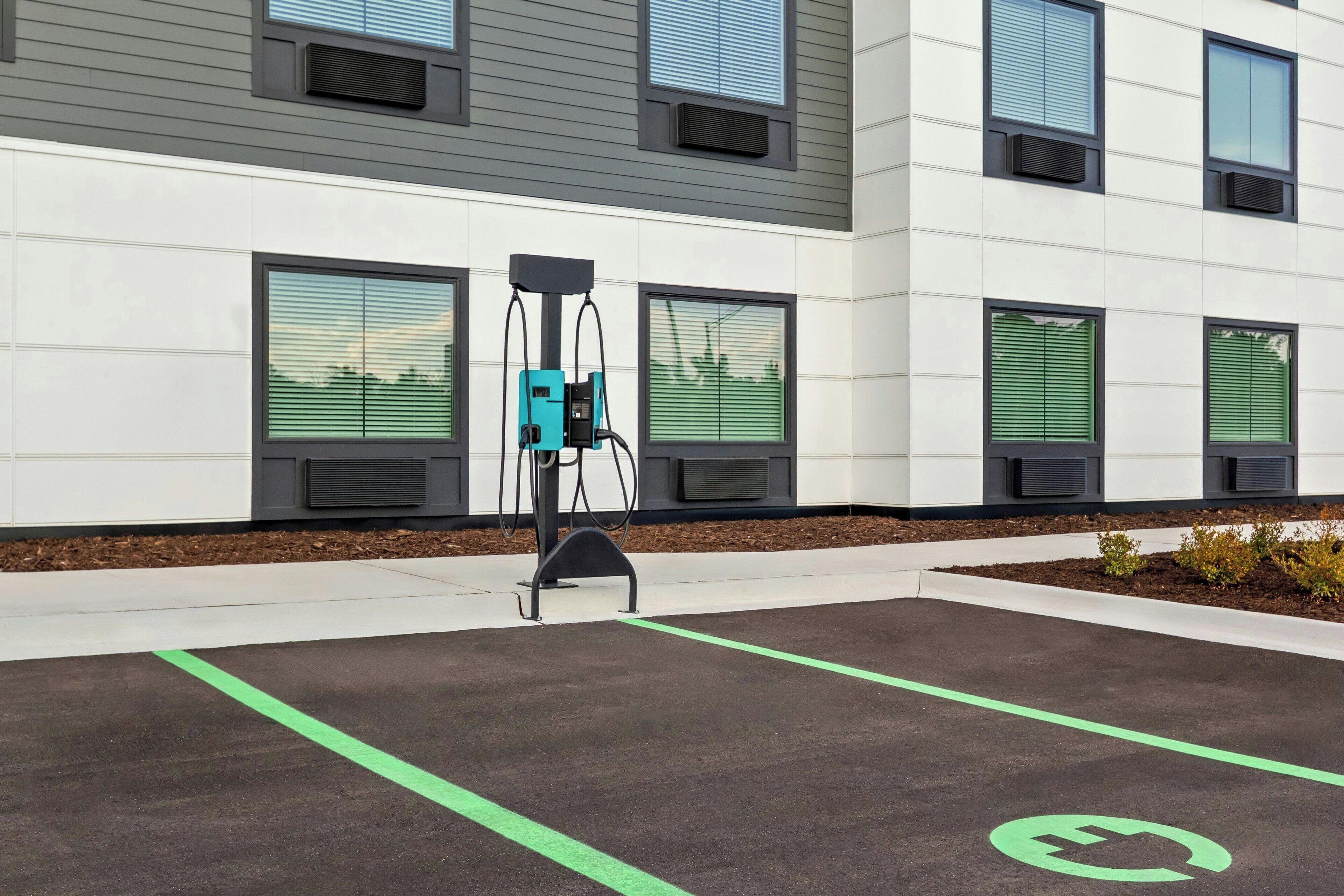 A modern building with a parking area marked for electric vehicle charging.