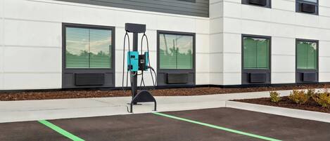 A modern building with a parking area marked for electric vehicle charging.