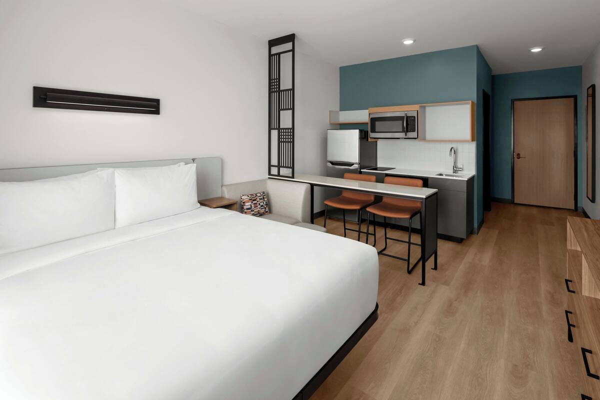 Une chambre d’hôtel moderne équipée d’un grand lit, d’un bureau avec deux chaises, d’un four à micro-ondes et d’un lavabo.