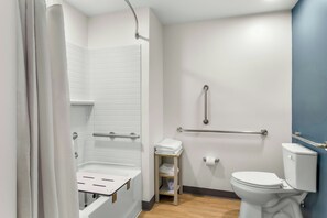 Une salle de bain moderne équipée d’une douche, de toilettes et de barres d’appui.