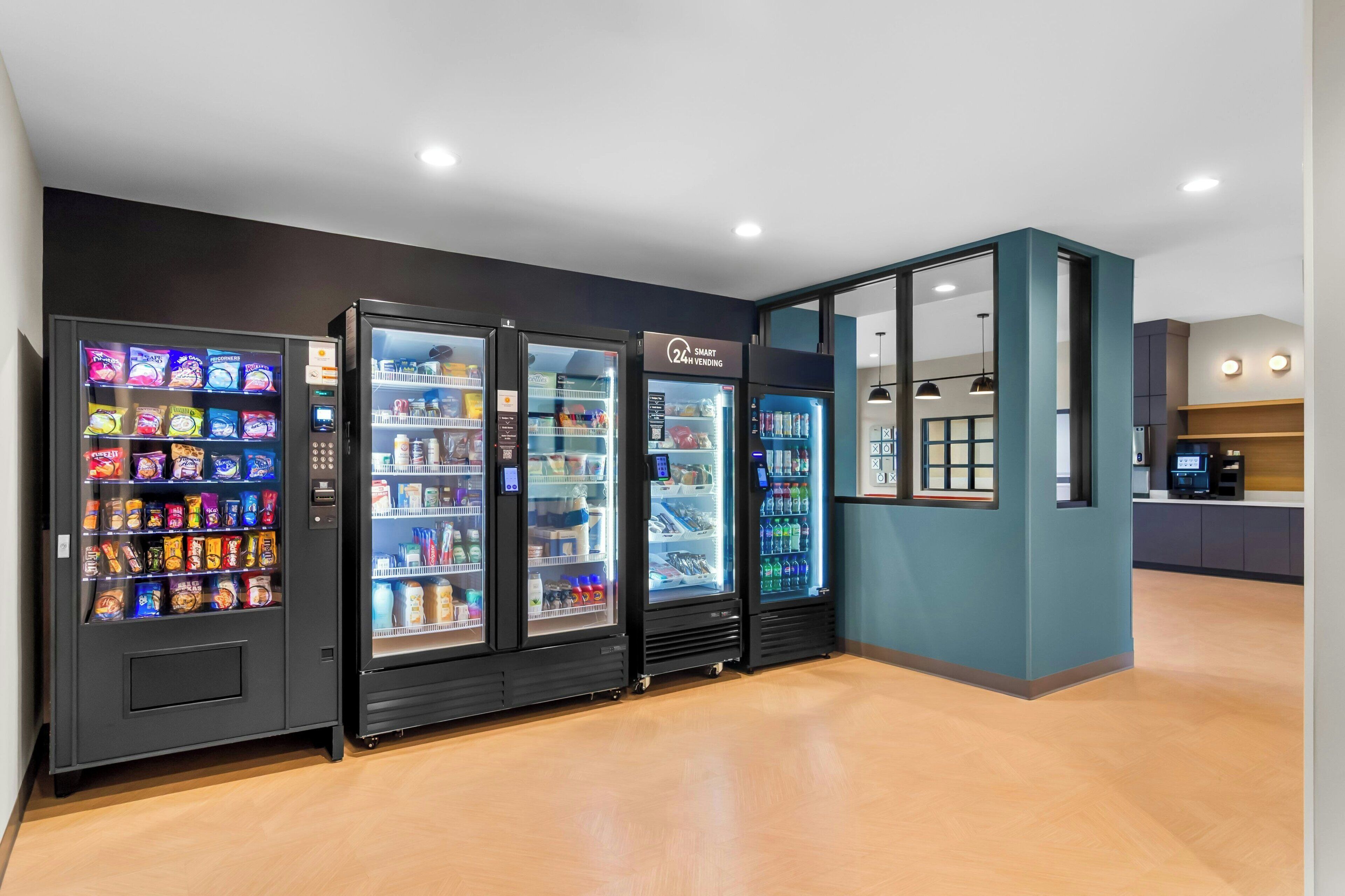 A row of vending machines in a modern interior with a wooden floor and a teal accent wall.