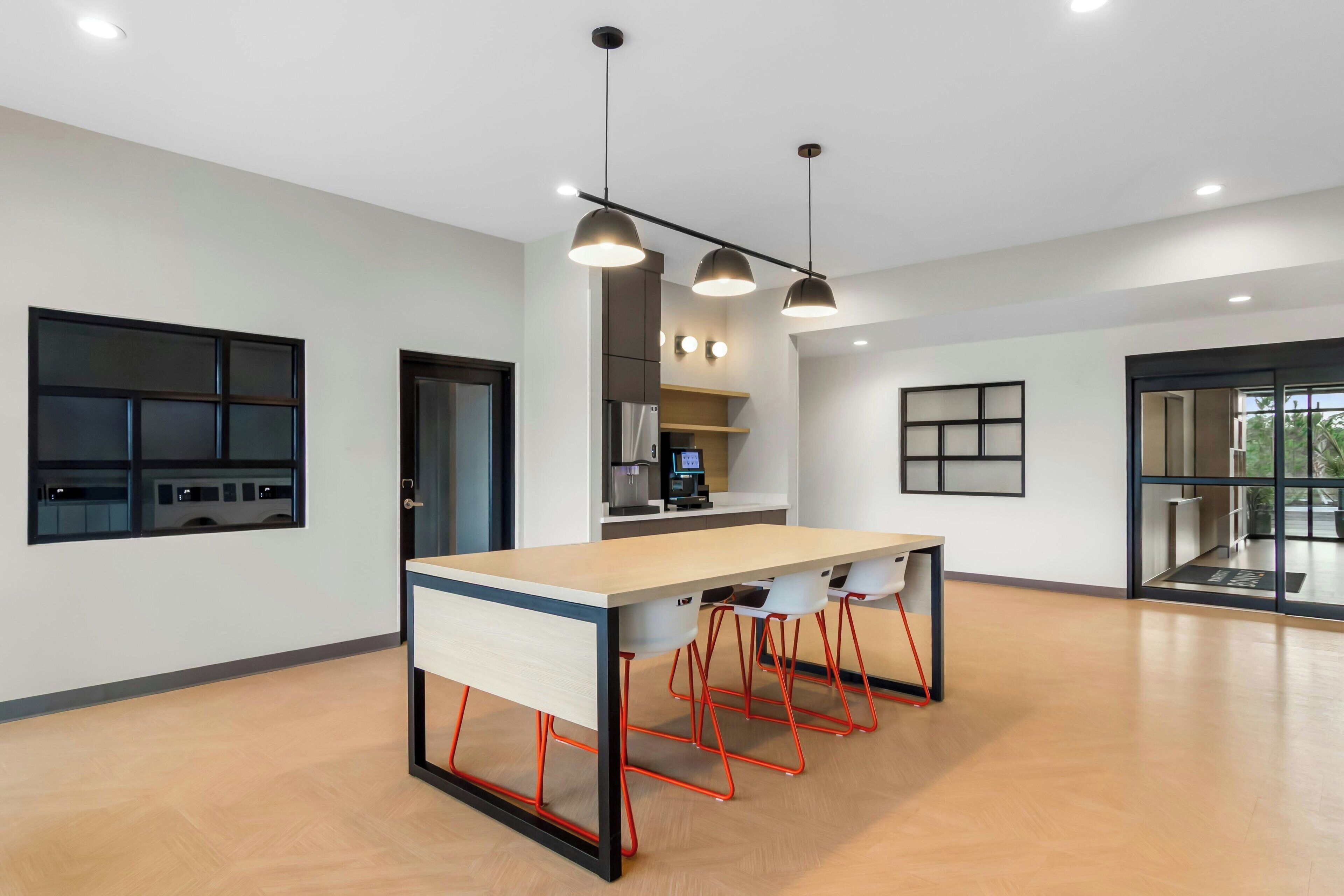 Una cocina moderna con una isla central, iluminación colgante y vistas al comedor.