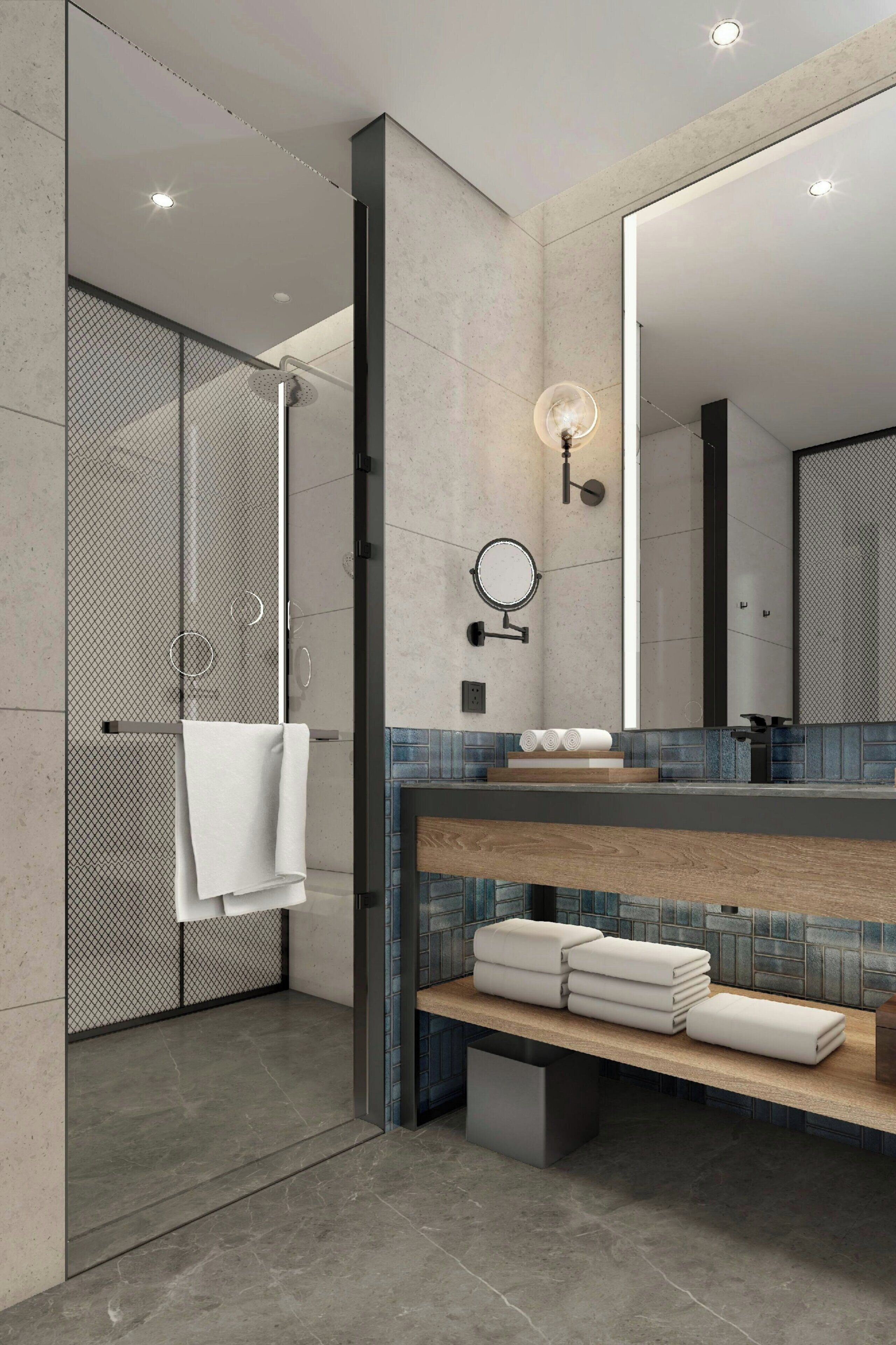 A modern bathroom with a glass-enclosed shower, a large mirror, and neatly stacked towels.