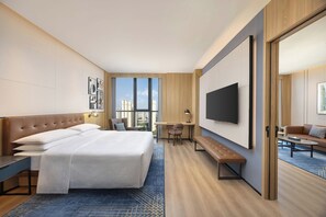 A modern hotel room with a large bed, a desk, a TV, and a view of the city. - Four Points By Sheraton Wuhan, Dongxihu (Wuhan)