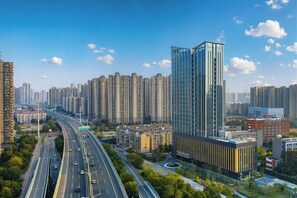 A high-rise building with a modern glass facade, surrounded by a dense urban skyline with numerous high-rise residential buildings. - Four Points By Sheraton Wuhan, Dongxihu (Wuhan)
