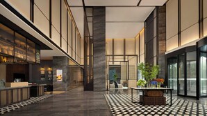 Un hall d’entrée spacieux avec un sol à carreaux, un comptoir de réception et un coin salon agrémenté d’une plante.
