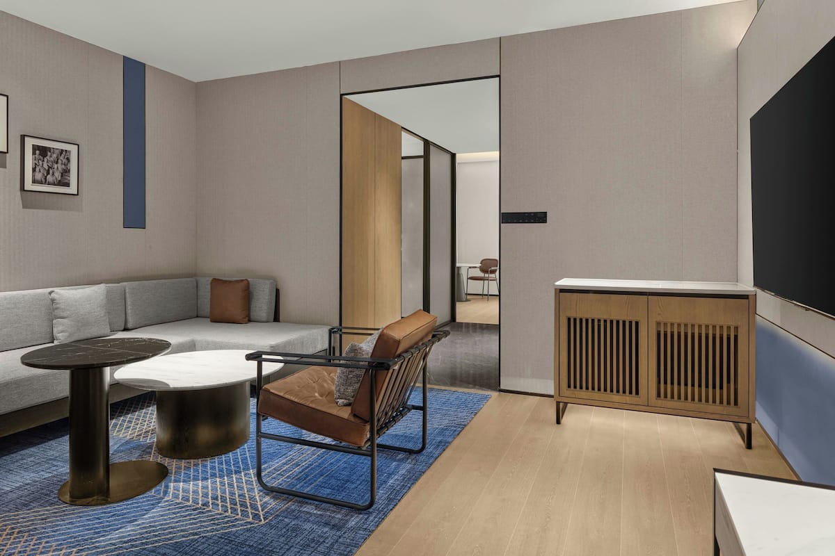 Una sala de estar moderna con sofá, mesa de centro, sillón, televisor y aparador de madera.