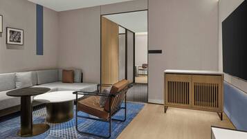 Una sala de estar moderna con sofá, mesa de centro, sillón, televisor y aparador de madera.