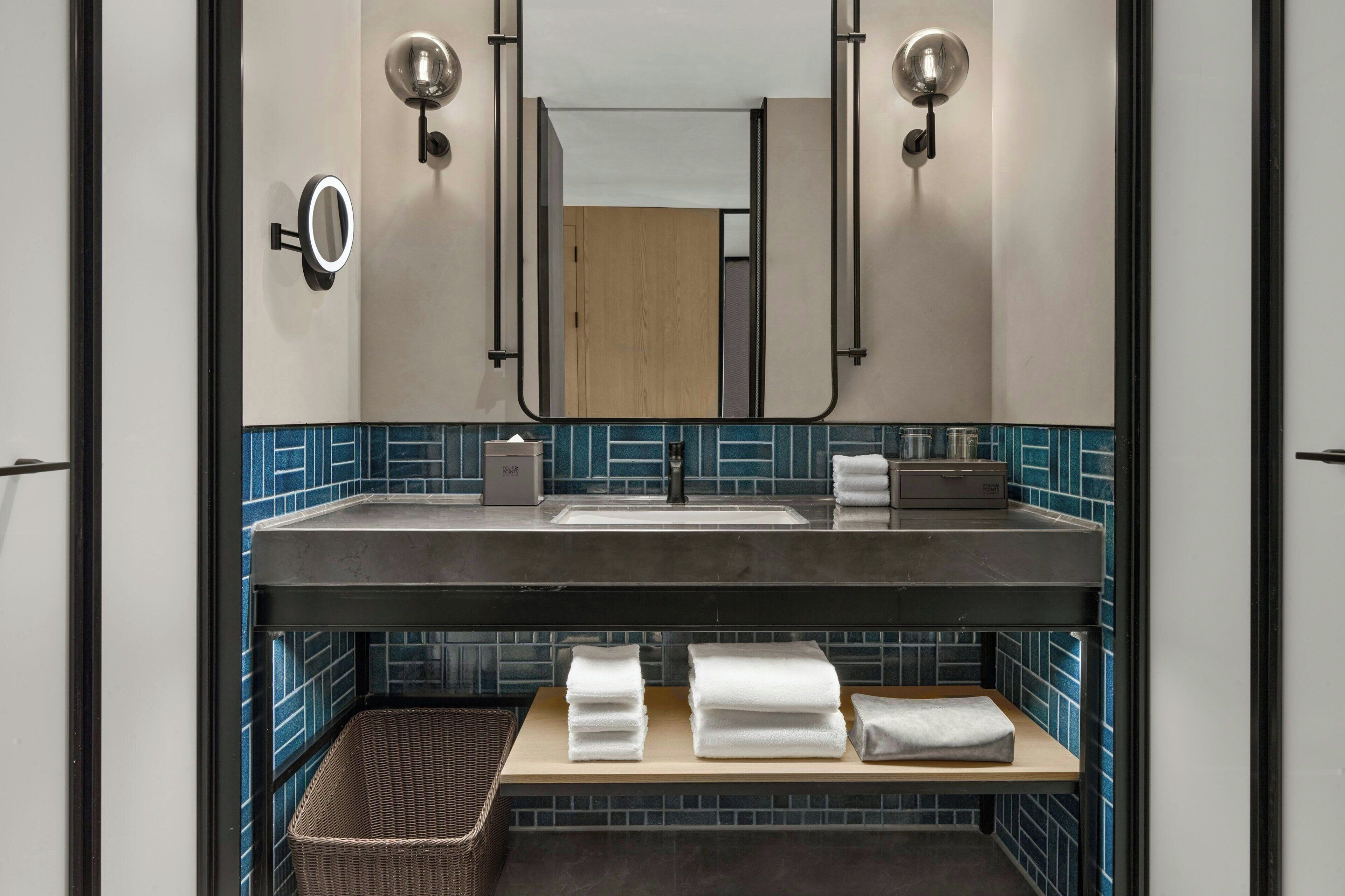Un bagno con uno specchio grande, un lavandino e un portascopevoli.