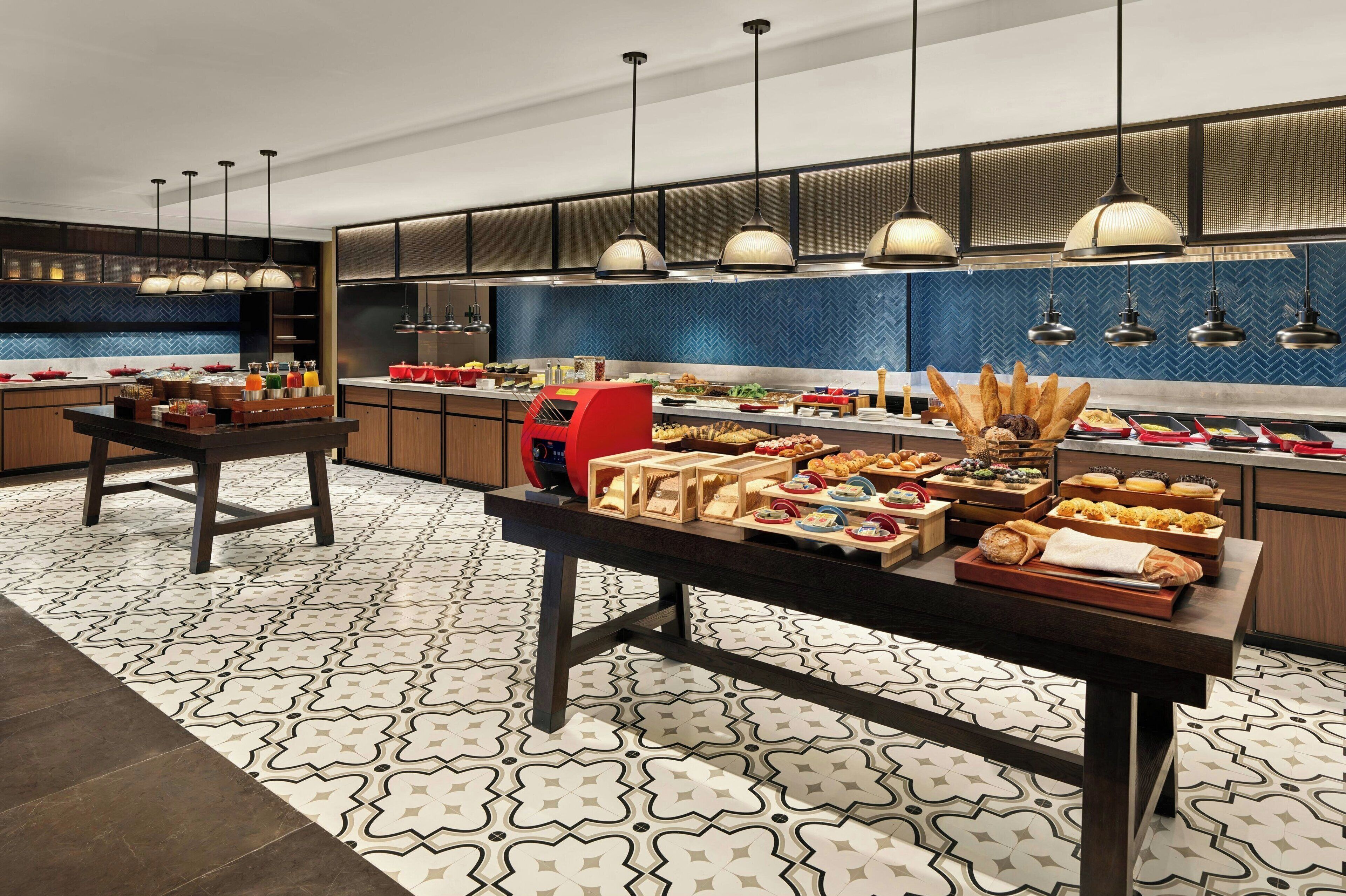 A modern kitchen with a central island, pendant lighting, and a blue herringbone tile backsplash.