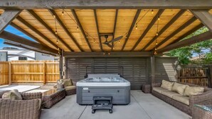 A covered patio area with a hot tub, wicker furniture, and a ceiling fan. - Cozy Master King suite- play room- hot tub (Denver)