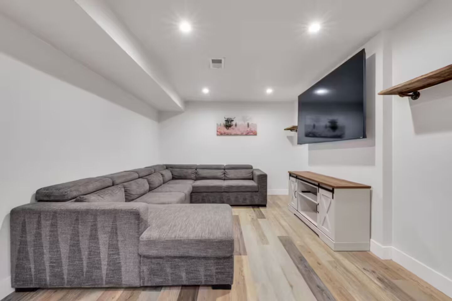 Una sala de estar moderna con un sofá modular, un mueble de madera y un televisor de pantalla plana montado en la pared.