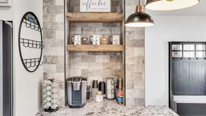 A kitchen with a coffee bar, a coffee machine, and various mugs on shelves. - Cozy Master King suite- play room- hot tub (Denver)