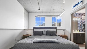 A bedroom with a large bed, two bedside tables, a window with a city view, and a wardrobe with patterned doors. - *NEW* Lux Loft V2 (Close to Vandy!) (Nashville)