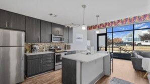 A modern kitchen with dark cabinets, stainless appliances, and a large island. - *NEW* Lux Loft V2 (Close to Vandy!) (Nashville)