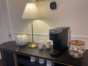 Eine Kaffeemaschine, eine Lampe und ein Dekoelement auf einem Tisch.