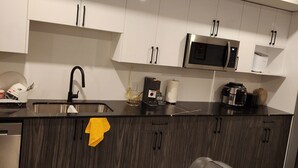 Una cocina moderna con armarios de madera oscura, electrodomésticos de acero inoxidable y encimera negra.