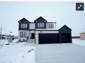A modern two-story house with a garage, numbered 821, in a snowy setting. - Cozy newly furnished 2-bedroom basement suite in West St. Paul. (West Saint Paul)