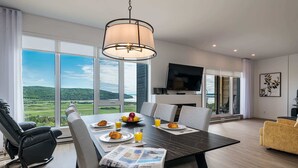 Een moderne eethoek met een grote tafel, stoelen en uitzicht op het platteland.