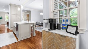 Una cocina moderna con una isla central, muebles blancos y un comedor con mesa y sillas.