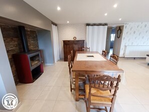 Ein geräumiger Essbereich mit einem langen Holztisch und Stühlen, einem Kamin und Blick auf das Wohnzimmer.