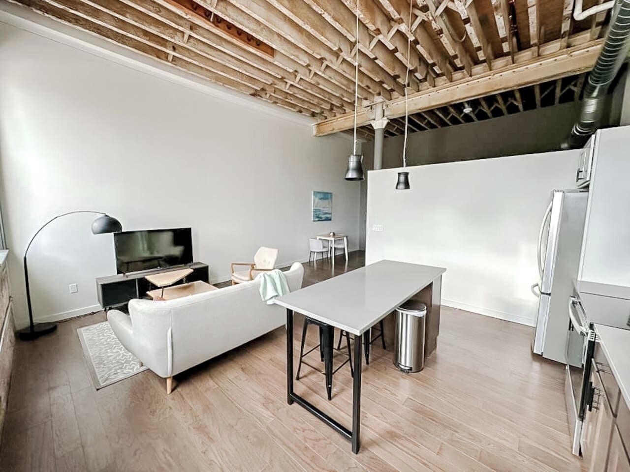 Une cuisine moderne avec un coin repas, des meubles blancs et un plafond en bois.