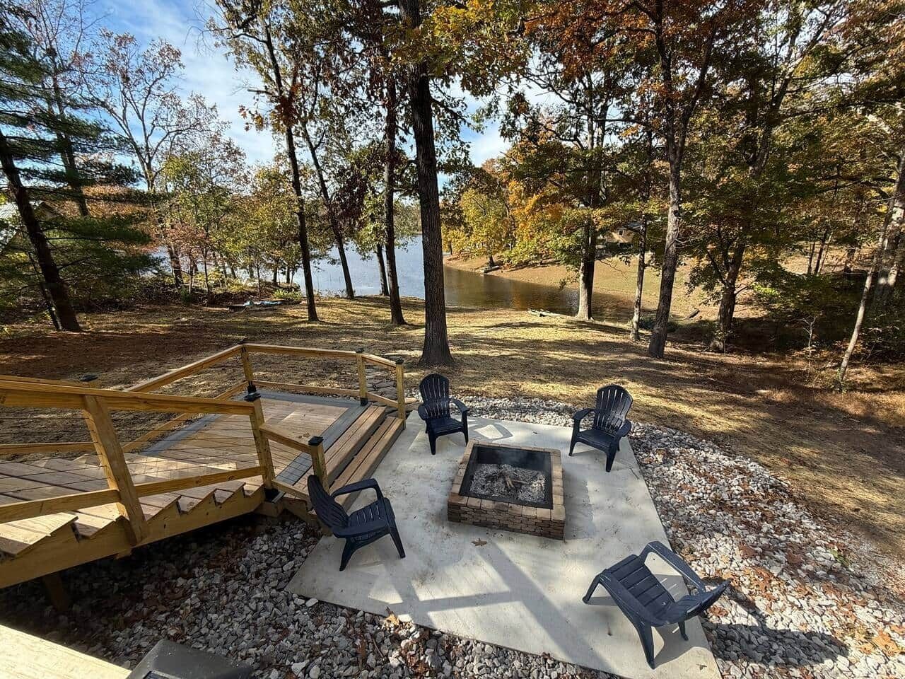 Una terraza con mobiliario exterior, un brasero y vistas a un lago rodeado de árboles.