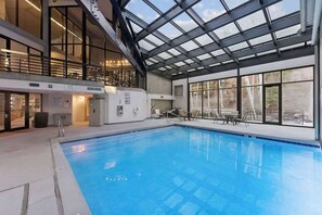 Ein Hallenbad mit Glasdach, einer Sonnenterrasse und Blick ins Freie.