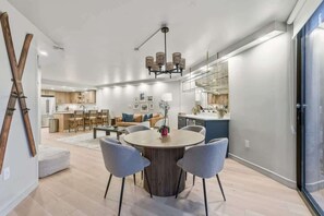 Una cocina moderna con comedor, una araña y un amplio ventanal.