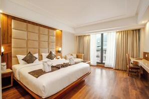 A spacious hotel room with a large bed, a desk, and a view of the outdoors. - Hotel Edisson View (New Delhi)