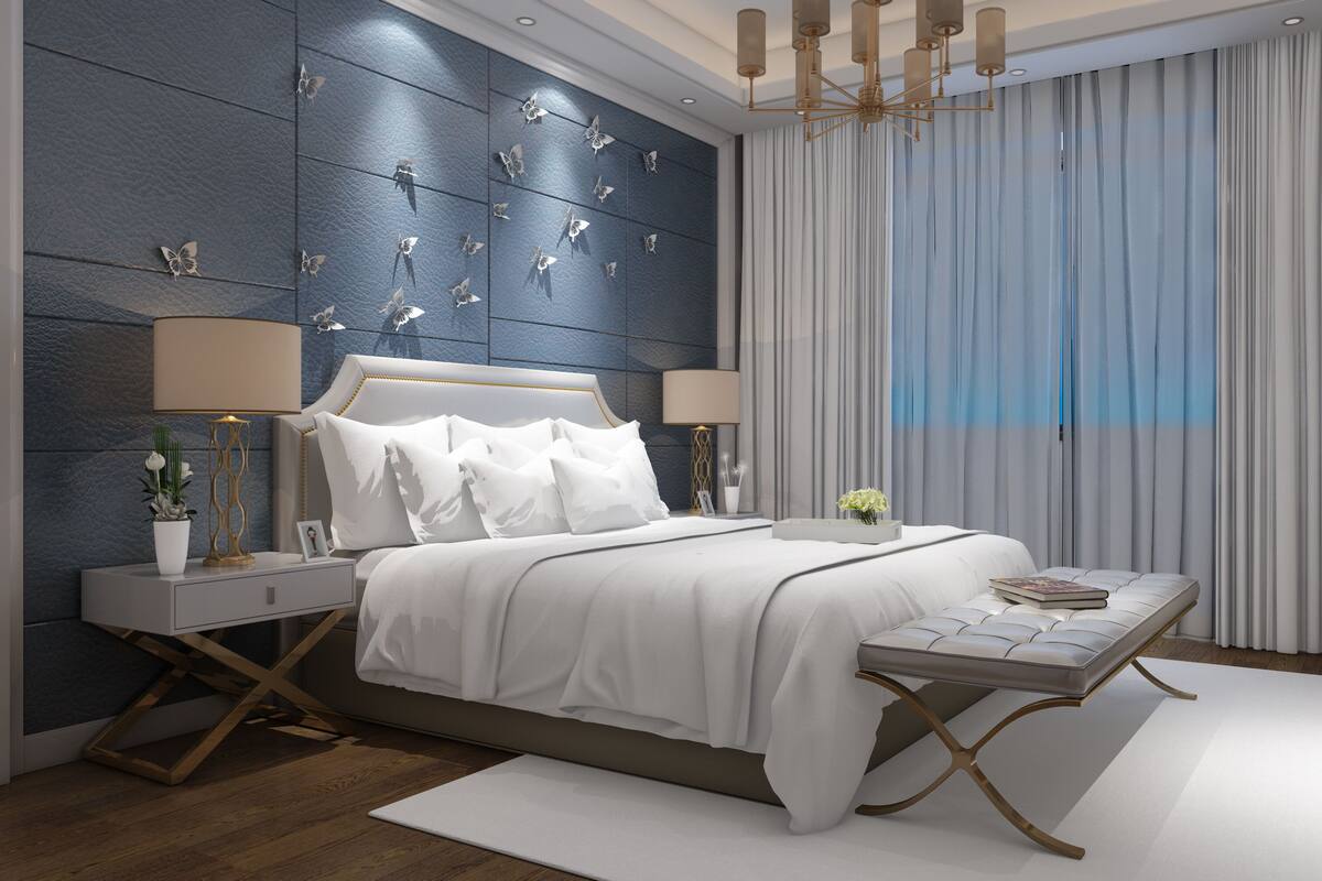 Un dormitorio moderno con cama, mesitas de noche, una lámpara, una bandeja con flores y un televisor.