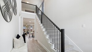 A spacious hallway with a staircase leading to an upper level. - Where Family Adventures Begin (Seagoville)