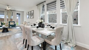 A dining area with a white table set for four, surrounded by tufted chairs. - Where Family Adventures Begin (Seagoville)