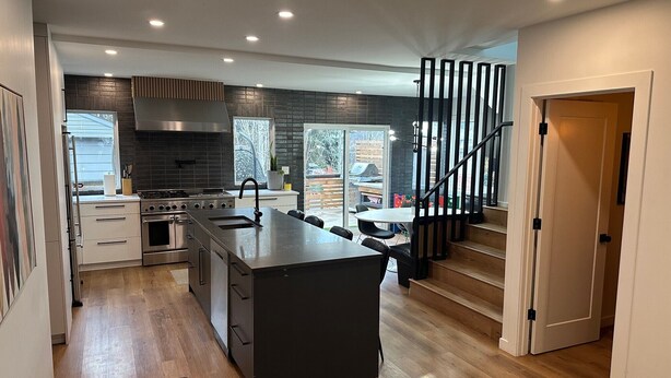 A modern kitchen with a central island, stainless steel appliances, and a staircase leading to a balcony.