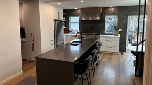 A modern kitchen with a central island, stainless steel appliances, and a view to the outdoors.